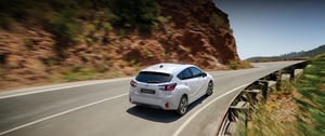 Subaru Impreza in weiß auf Bergstraße im Sommer