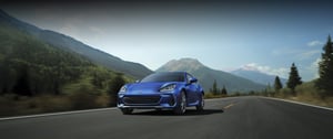 Subaru BRZ als blaues Sportcoupé auf Landstraße mit Bergen im Hintergrund