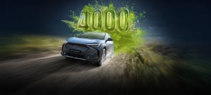 Subaru Solterra fährt auf Straße, dahinter große grüne Zahl '4000€'