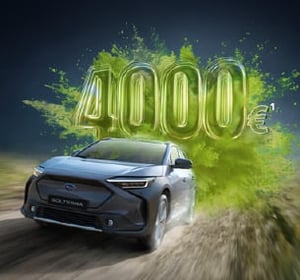 Subaru Solterra fährt auf Straße, dahinter große grüne Zahl '4000€' und Umweltbonus Signet daneben