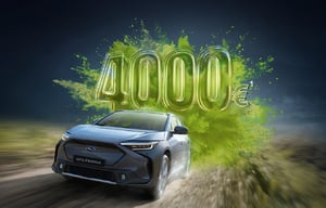 Subaru Solterra fährt auf Straße, dahinter große grüne Zahl '4000€'