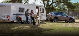 Subaru Outback mit Caravan und Familie davor